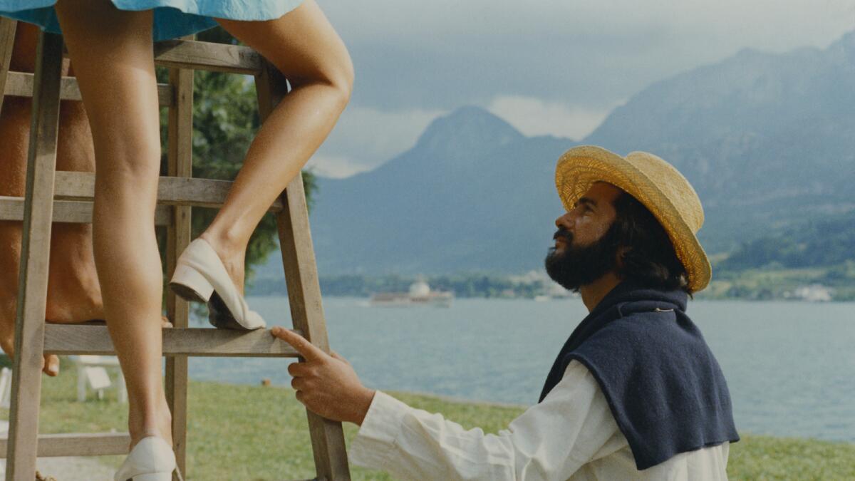A man looks intensely at a woman's knee while she stands on a ladder.
