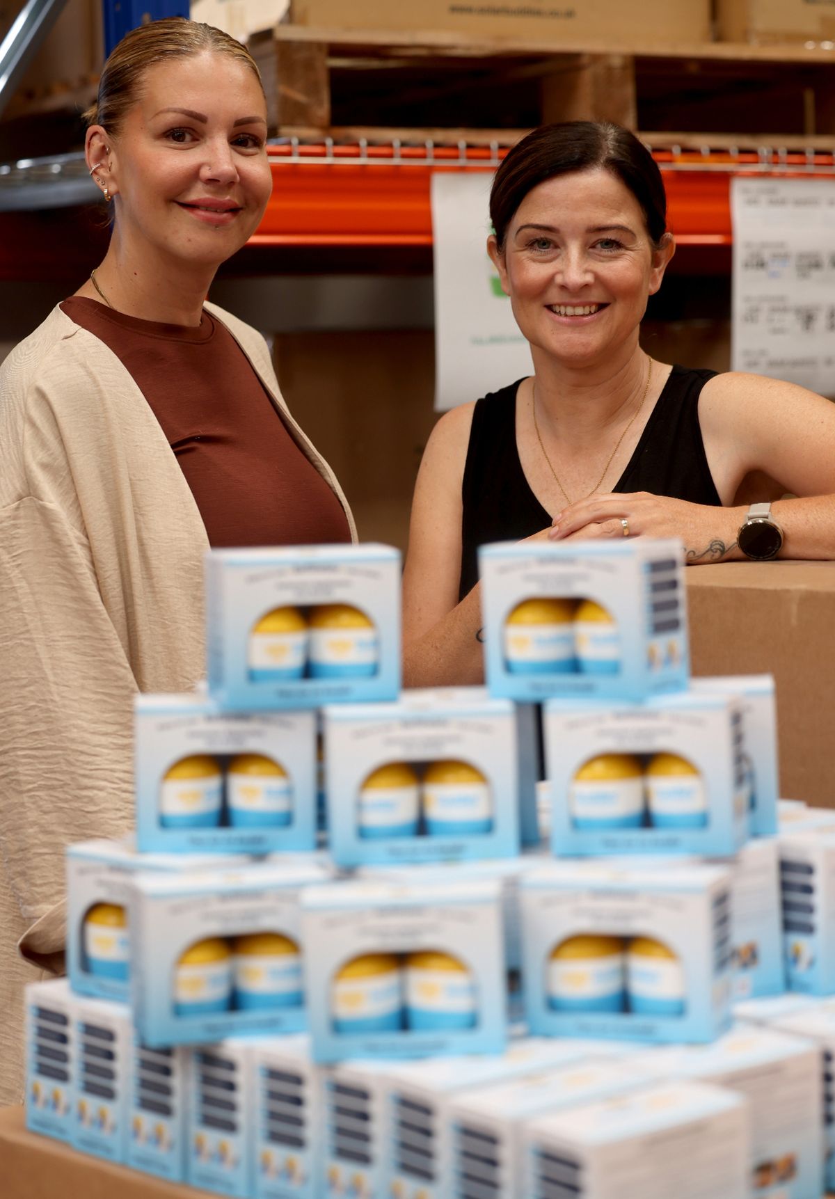 Two smiling women stood by boxes