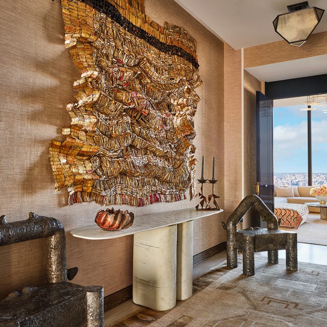 Sophisticated interior with textured metallic wall art, unique furniture, and a distant cityscape view.