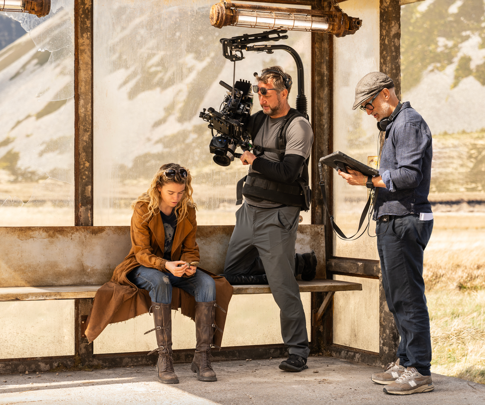 Filmmaker directing scene with cast and crew at a bus stop set.