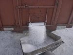 Urea fertilizer drops from the partially-opened gate on the box of a truck into the hopper of an unseen auger.