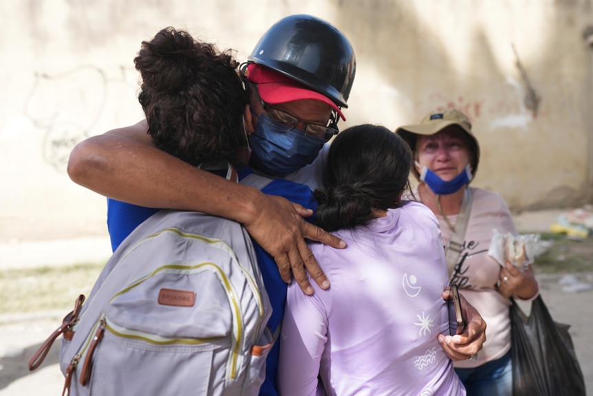 a man hugs his wife and young daughter after being separated for three days.