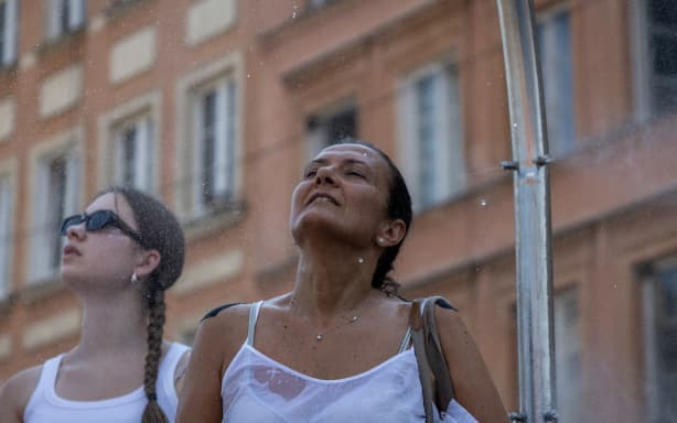 Women cool off under a water curtain on the Royal Castle Square in Warsaw's Old Town as thermometers show record temperatures during a heatwave that has reached Poland on June 28, 2026