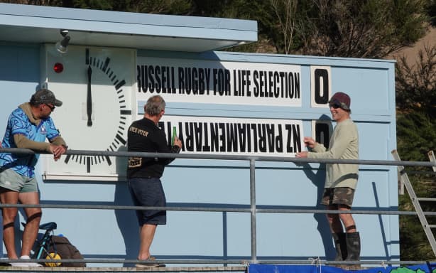 I’m sure it goes this way up … Match officials prepare the club’s scoreboard.