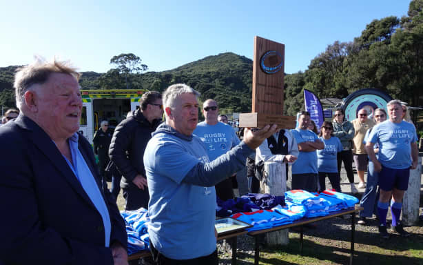 Russell Sports Club’s Gary Hooson shows off the Grahame Thorne trophy while ex All Black Grahame Thorne himself looks on.
