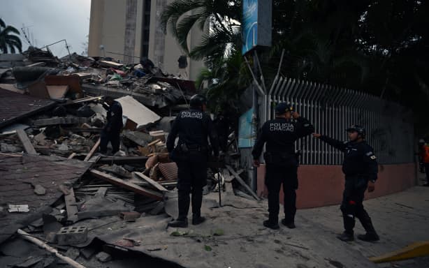 Municipal police officers stand next to the remains of a collapsed structure following an earthquake in Caracas on June 24, 2026. A magnitude 7.1 earthquake struck Venezuela on Wednesday, the United States Geological Survey (USGS) reported, triggering panic in Caracas, according to AFP journalists. The tremor, which was followed by several aftershocks, was also felt in Colombia. (Photo by Juan BARRETO / AFP)