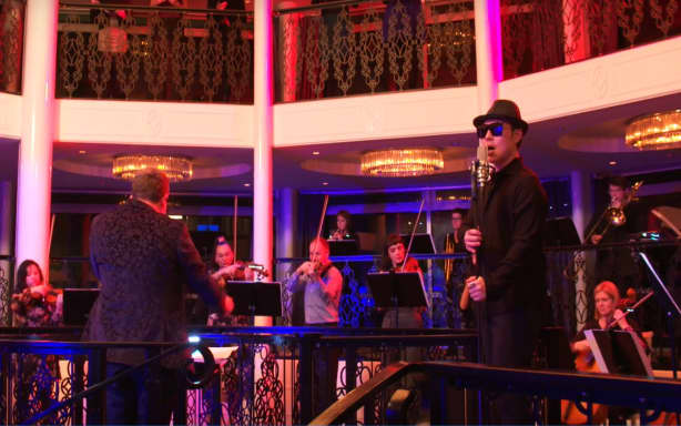 A screenshot from a video of Liu and dozens of paid musicians at a recording session at a wedding venue in Northcote Point, Auckland.