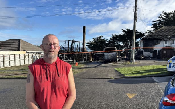 The aftermath of a fire in Spur Grove, Tītahi Bay, Porirua, on 21 June 2026, which badly damaged a house and a caravan on neighbouring properties the night before.