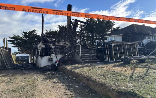 The aftermath of a fire in Spur Grove, Tītahi Bay, Porirua, on 21 June 2026, which badly damaged a house and a caravan on neighbouring properties the night before.