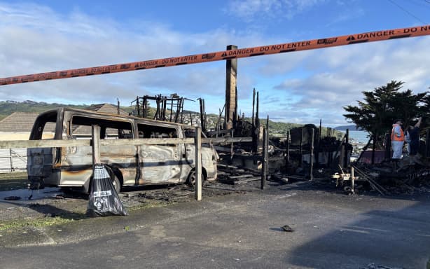 The aftermath of a fire in Spur Grove, Tītahi Bay, Porirua, on 21 June 2026, which badly damaged a house and a caravan on neighbouring properties the night before.