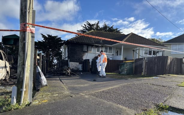 The aftermath of a fire in Spur Grove, Tītahi Bay, Porirua, on 21 June 2026, which badly damaged a house and a caravan on neighbouring properties the night before.