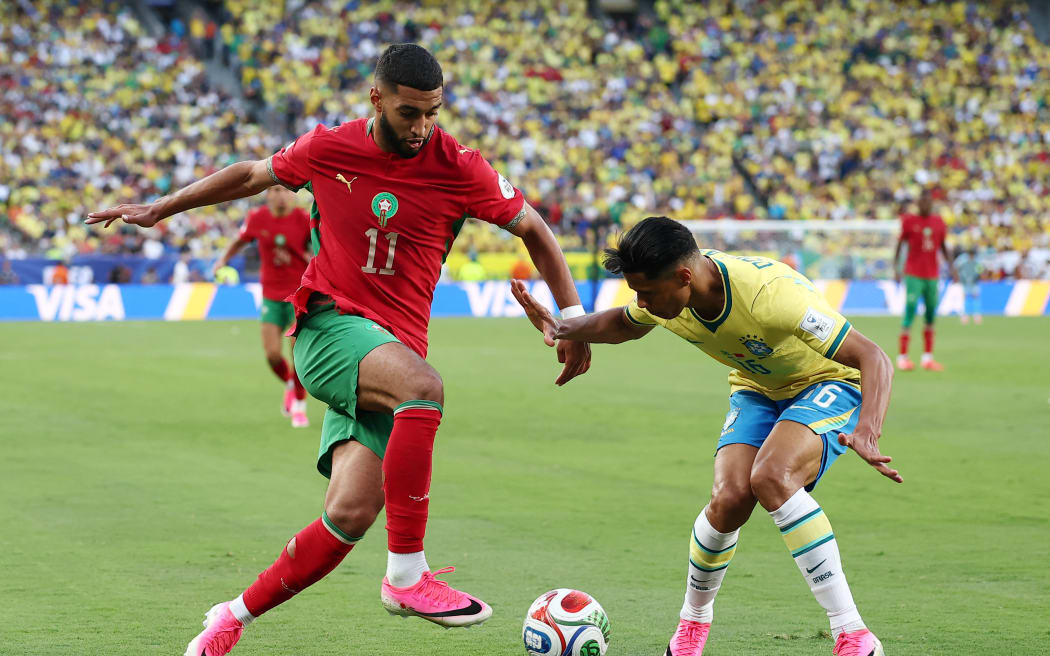 Morocco midfielder Ismael Saibari (L) and Brazil defender Douglas Santos fight for the ball during the 2026 World Cup Group C football match at the New York/New Jersey Stadium, 14 June, 2026. (Photo by CHARLY TRIBALLEAU / AFP)