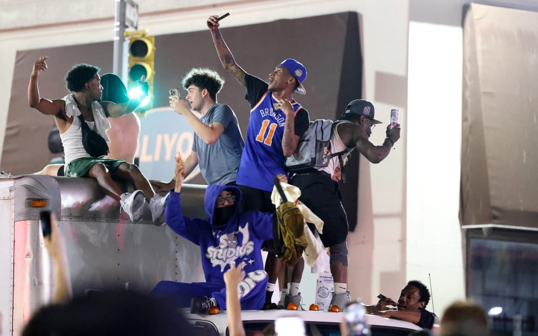 New York Knicks fans climb on a truck as they celebrate outside Madison Square Garden after their team’s Game 4 victory over the San Antonio Spurs in the NBA Finals in New York on June 10, 2026. (Photo by CHARLY TRIBALLEAU / AFP)