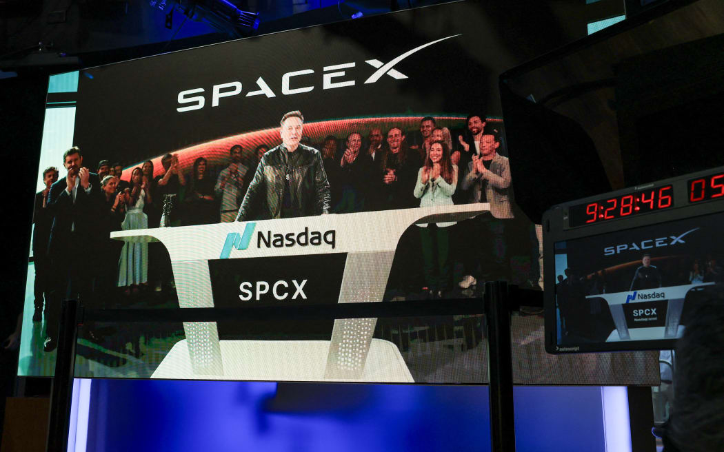 SpaceX CEO Elon Musk, displayed on a screen remotely from SpaceX headquarters in Starbase, Texas, speaks before the launch of SpaceX’s initial public offering (IPO) at the Nasdaq MarketSite in New York on June 12, 2026. Elon Musk's SpaceX begins trading on the Nasdaq exchange on Friday with the biggest initial public offering in history expected to make the polarizing entrepreneur the world's first trillionaire. The company priced more than 555 million shares at $135 each in a filing with the US markets regulator on Thursday, placing SpaceX in the top 10 of Wall Street's biggest companies with a valuation of just under $1.8 trillion -- ahead of Tesla, Facebook-owner Meta and Walmart. (Photo by TIMOTHY A. CLARY / AFP)