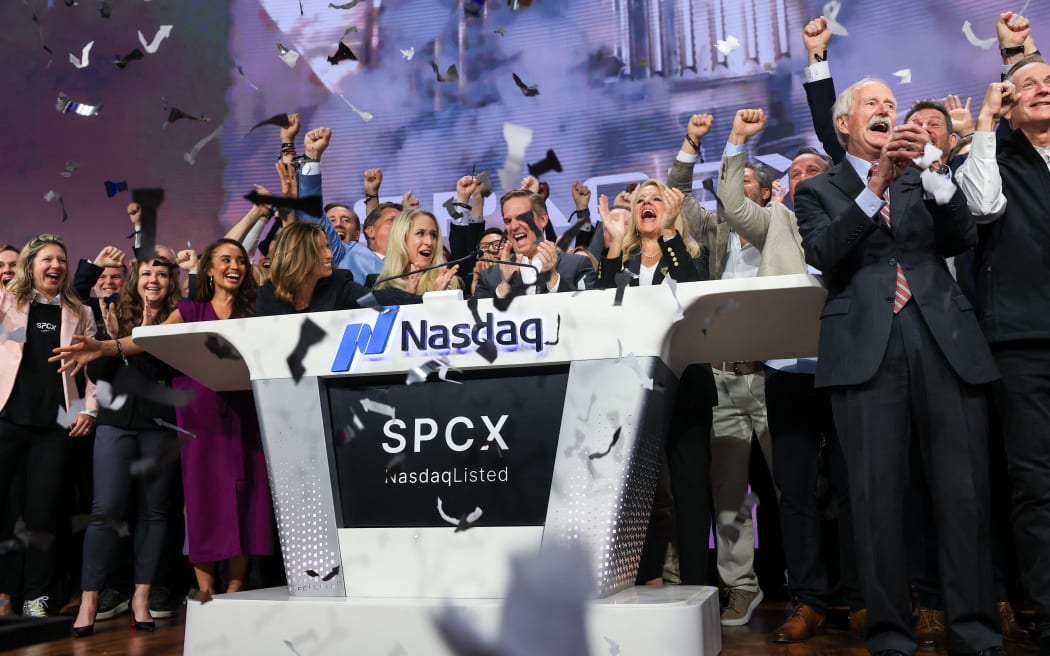 Bret Johnsen (C), SpaceX Chief Financial Officer, and Gwynne Shotwell (center R), SpaceX President and Chief Operating Officer, celebrate with SpaceX employees as they ring the opening bell at the Nasdaq MarketSite to celebrate the launch of SpaceX’s initial public offering (IPO) in New York on June 12, 2026. Elon Musk's SpaceX begins trading on the Nasdaq exchange on Friday with the biggest initial public offering in history expected to make the polarizing entrepreneur the world's first trillionaire. The company priced more than 555 million shares at $135 each in a filing with the US markets regulator on Thursday, placing SpaceX in the top 10 of Wall Street's biggest companies with a valuation of just under $1.8 trillion -- ahead of Tesla, Facebook-owner Meta and Walmart. (Photo by TIMOTHY A. CLARY / AFP)