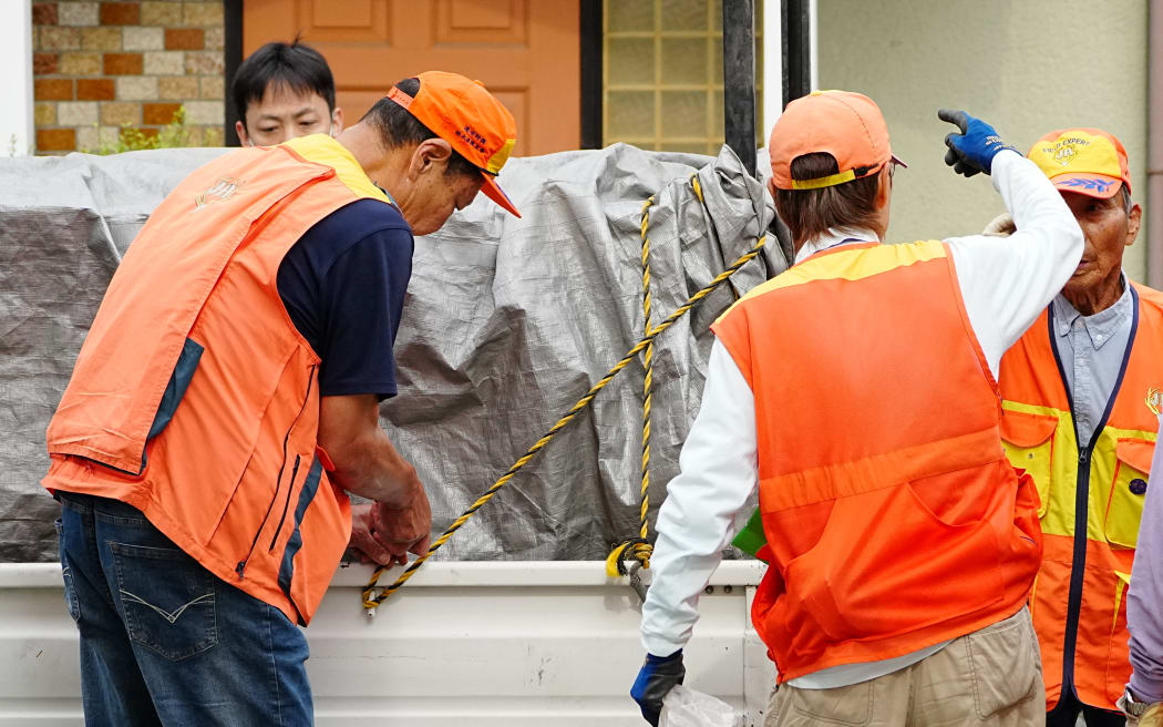 Hunters stand next to a truck carrying a sedated wild bear after it was captured in Utsunomiya, north of Tokyo, on June 9, 2026. A bear roaming the streets of a Japanese city for days forced the closure of nearly 100 schools, as dozens of hunters and officials searched for the animal. (Photo by Yuichi YAMAZAKI / AFP)