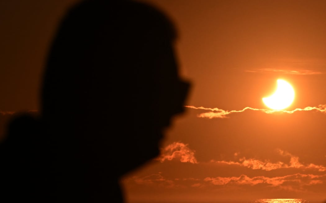 A person watches a partial solar eclipse at New Brighton, a coastal suburb of Christchurch, on September 22, 2025. A solar eclipse occurs when the moon passes between Earth and the sun, casting a shadow on our planet. This solar eclipse was visible to parts of the Pacific, Atlantic, Australia and Antarctica.