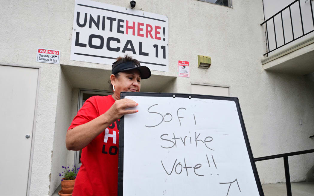 Yolanda Fierro, a suites runner at SoFi Stadium, moves a sign into position at union headquarters where stadium workers will vote on whether to authorize a strike amid a contract dispute, days before the 2026 FIFA World Cup begins in Inglewood, California, on June 4, 2026. Hundreds of workers at Los Angeles’ SoFi Stadium began voting on June 4 on a proposal to go on strike during the World Cup, which kicks off in a week, after negotiations over their safety and wage demands reached an impasse. The vote was taking place at the offices of the Unite Here Local 11 union in Inglewood (south of Los Angeles) and will continue until Friday night. (Photo by Frederic J. BROWN / AFP)