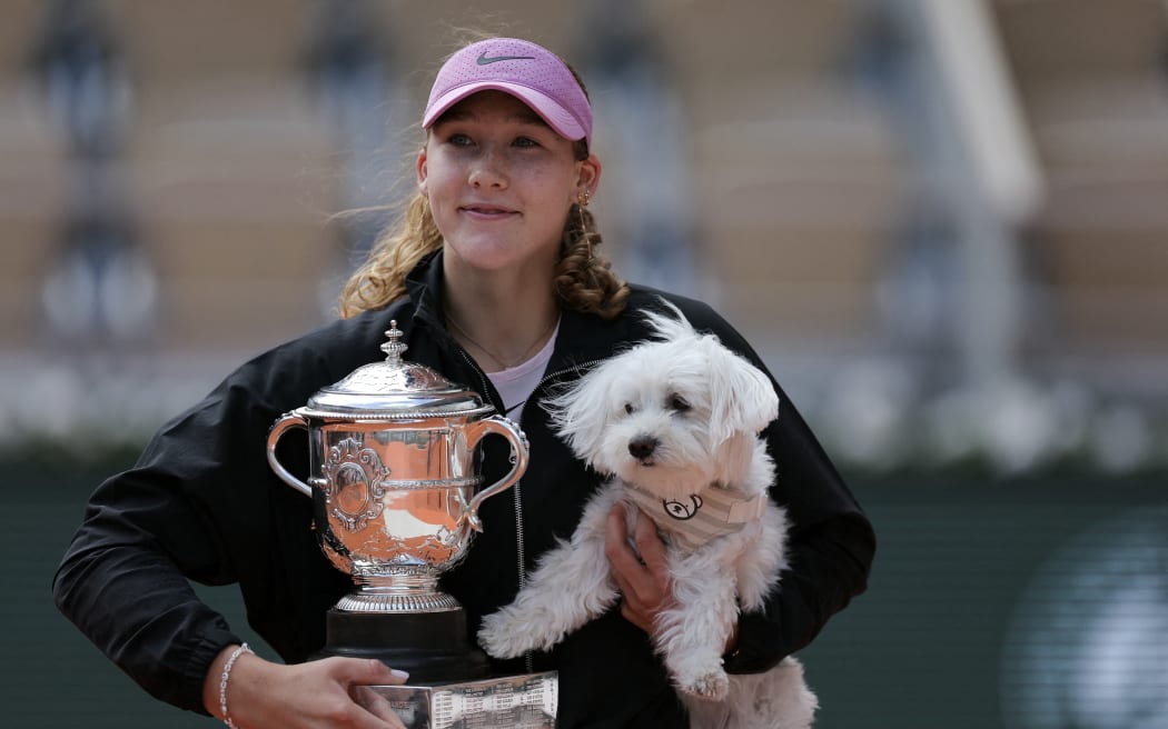 Russia's Mirra Andreeva poses with the Coupe Suzanne Lenglen (Suzanne Lenglen Trophy) and her dog after winning the French Open tennis tournament women's singles final match against Poland's Maja Chwalinska on day 14 of the French Open tennis tournament on Court Philippe-Chatrier at the Roland-Garros Complex in Paris on June 6, 2026. (Photo by Thomas SAMSON / AFP)