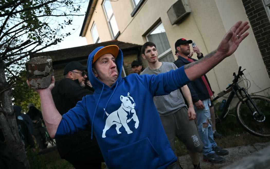 A demonstrator throws a brick at police near Portswood Police Station, following a protest march in Southampton, southern England, on June 2, 2026, held in reaction to the Police's handling of the detention of victim Henry Nowak, following the conviction of his murderer Vickrum Digwa. Body camera footage of dying student Henry Nowak, who was handcuffed by British police after being stabbed by Sikh man Vickrum Digwa, and falsely accused of racially abusing his murderer sparked outrage Tuesday. (Photo by JUSTIN TALLIS / AFP)