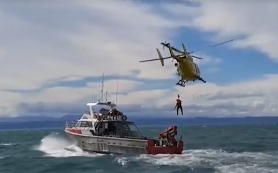 A medic is lowered to a boat involved in the recovery of two men from the water off Napier on October 21 last year.