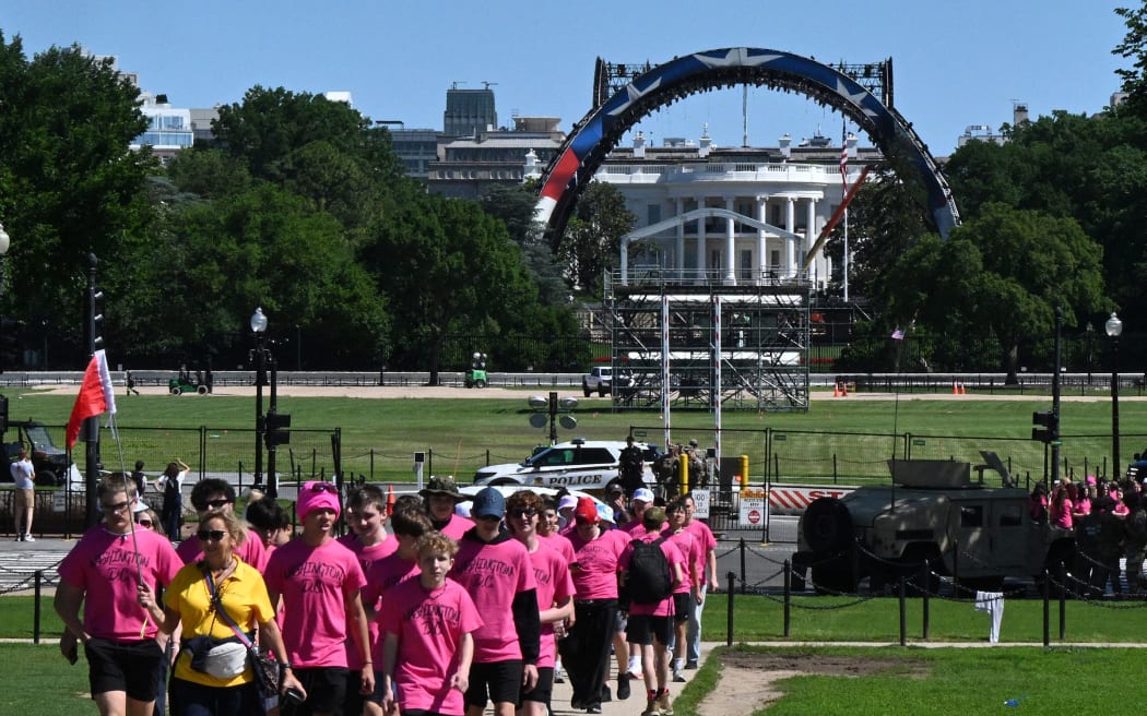 Visitors walk near the White House as cranes work on the construction on the South Lawn of the White House on May 29.