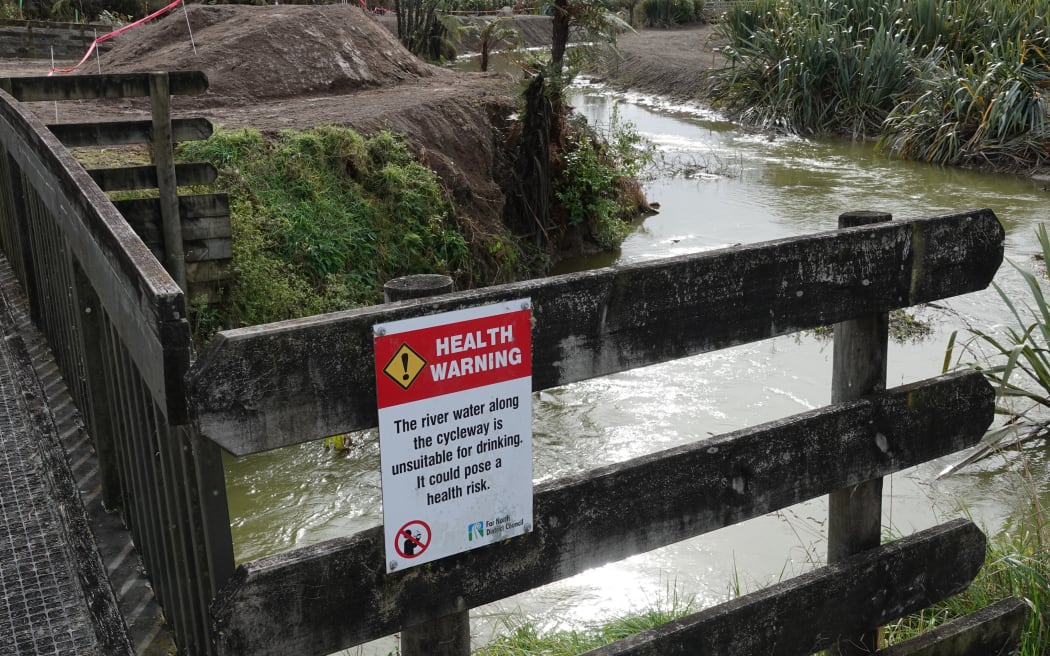 A warning sign where Pou Herenga Tai-Twin Coast Cycle Trail crosses the lake outlet.