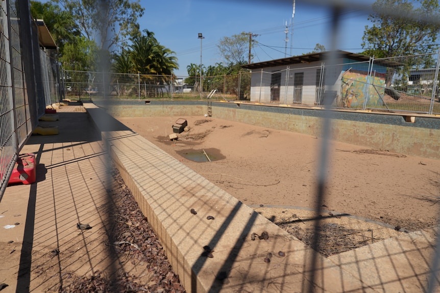 A large empty outdoor pool is full of mud