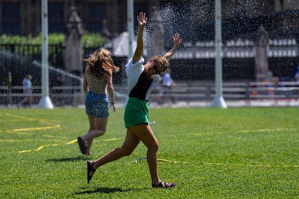 People run through a sprinkler in London’s Parliament Square on Wednesday.