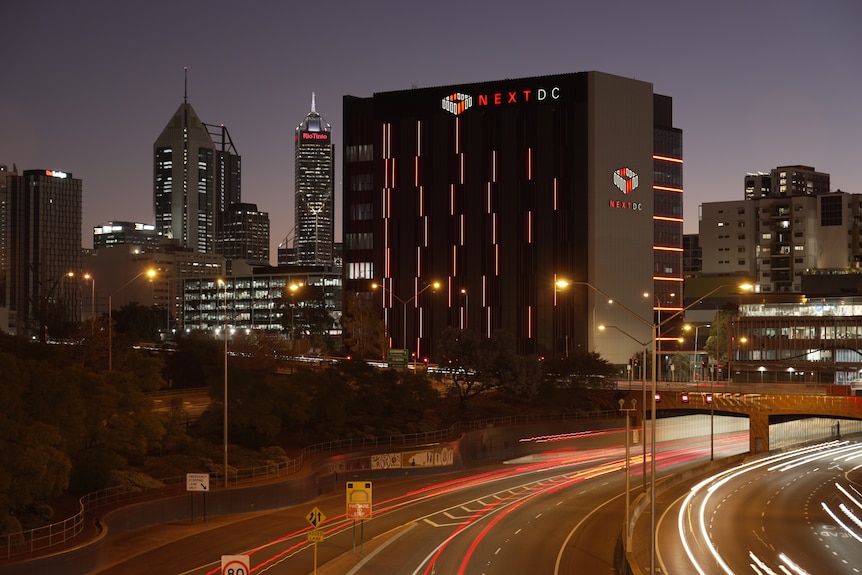 Picture of a high-rise NextDC data centre next to freeway tunnel entrance with city skyline in background