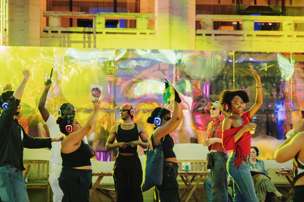 People dancing with headphones at a colorful silent disco event.