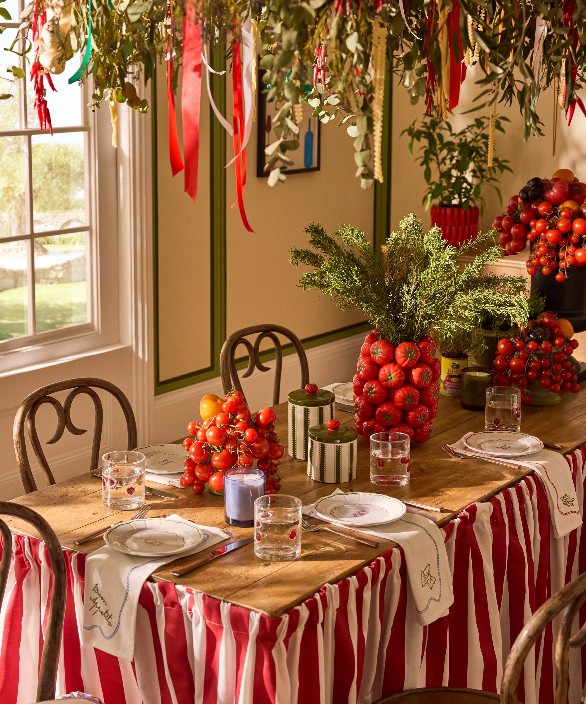 A dining room with a rustic dining table with side plates, napkins and tomato vase from Lia Gold's collection for Next
