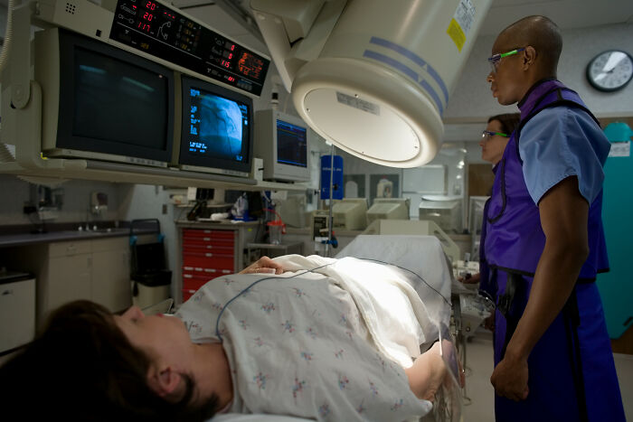 A patient lies on a bed as nurses monitor medical screens, showcasing things that happened with patients.