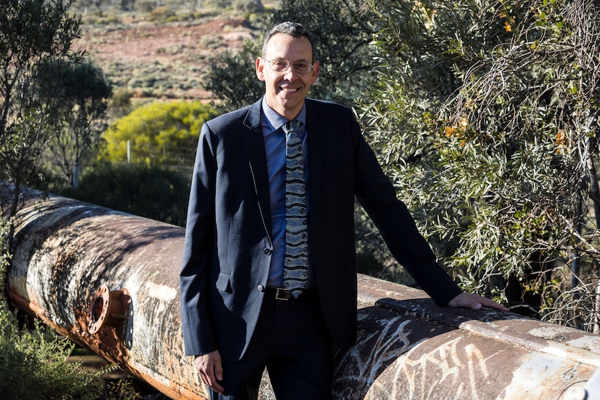 An executive from Water Corporation in a suit and tie standing next to a water pipeline.