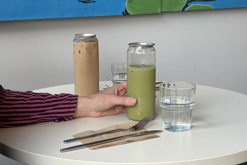 Two can-shaped plastic drinking vessels with metal pull tab tops on a table.