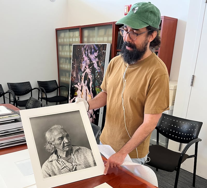 Victor Rivera, exhibitions and collection manager at Light Work, holds Chief Lewis Farmer, Eel Clan, Onondaga, 1991, Toba Pato Tucker.