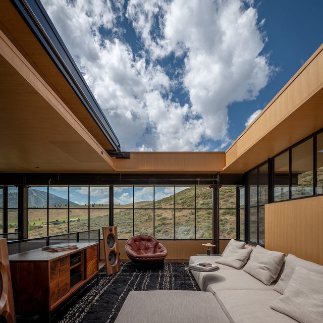 Modern living room with large windows, mountain view, and comfortable seating.