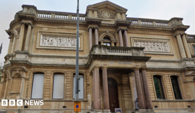 A photo of the exterior of a two-storey Victorian building which has a sign saying 'art gallery on it'. The building has marble pillars.