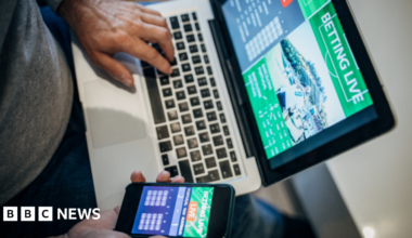 Man accessing gambling platforms online via laptop and phone app.
