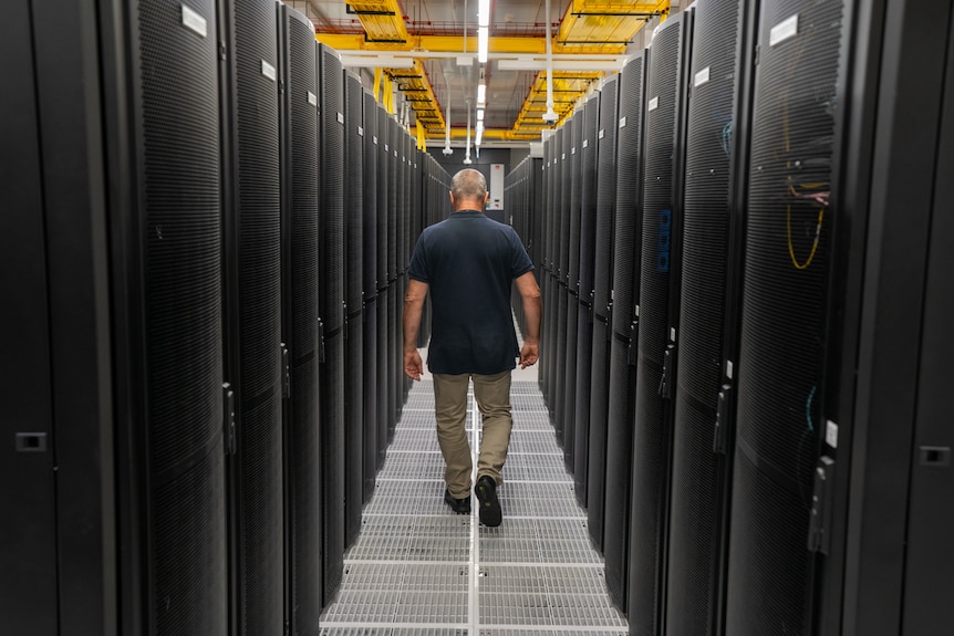 a man walks between rows of servers