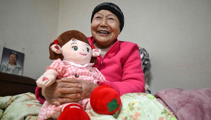 This picture taken on April 29, 2026, shows Kim Young-bun, a South Korean elderly woman living alone, holding Hyodol, an AI-powered healthcare doll designed for elderly people, during an interview with AFP at her home in Yongin, South Korea. — AFP