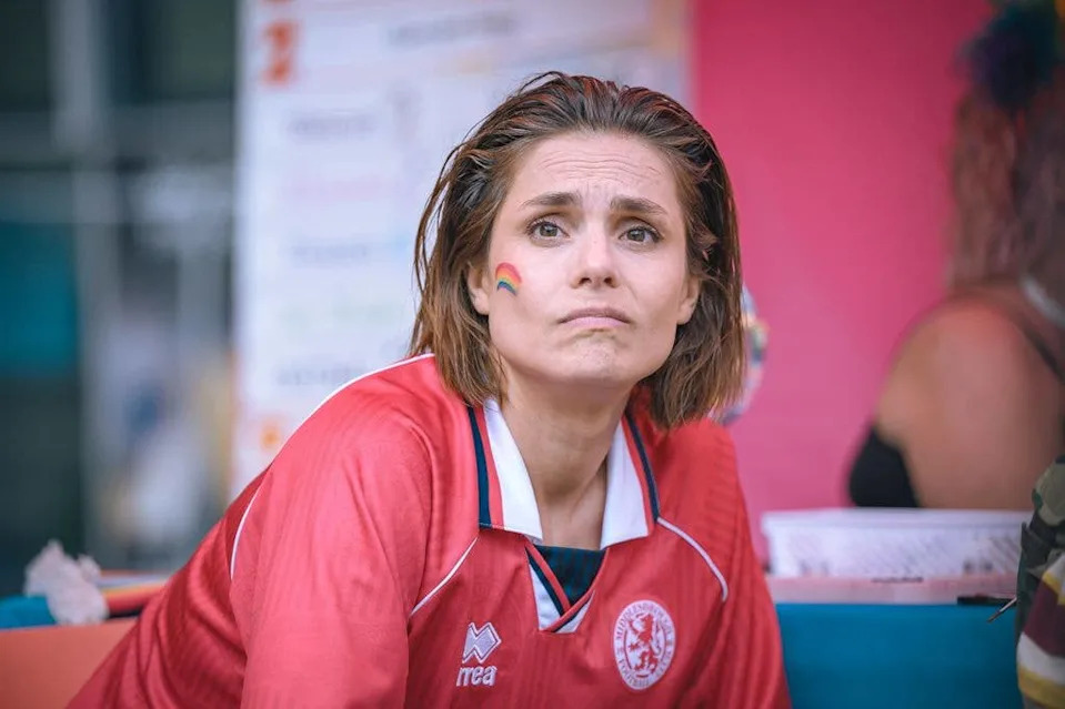 Woman in football shirt with rainbow painted on face