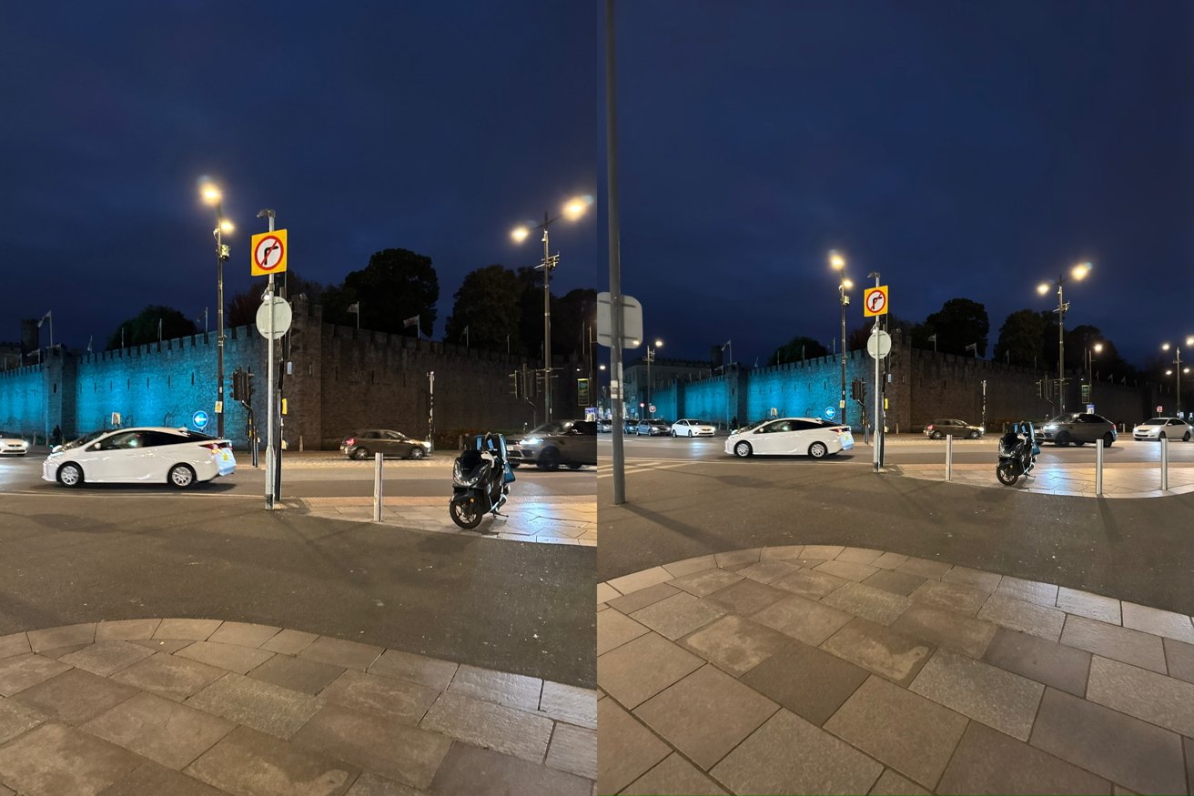 Nighttime city street with cars and motorcycles, bright streetlights, a glowing blue-lit stone wall in the background, traffic signs, and tiled sidewalk in the foreground
