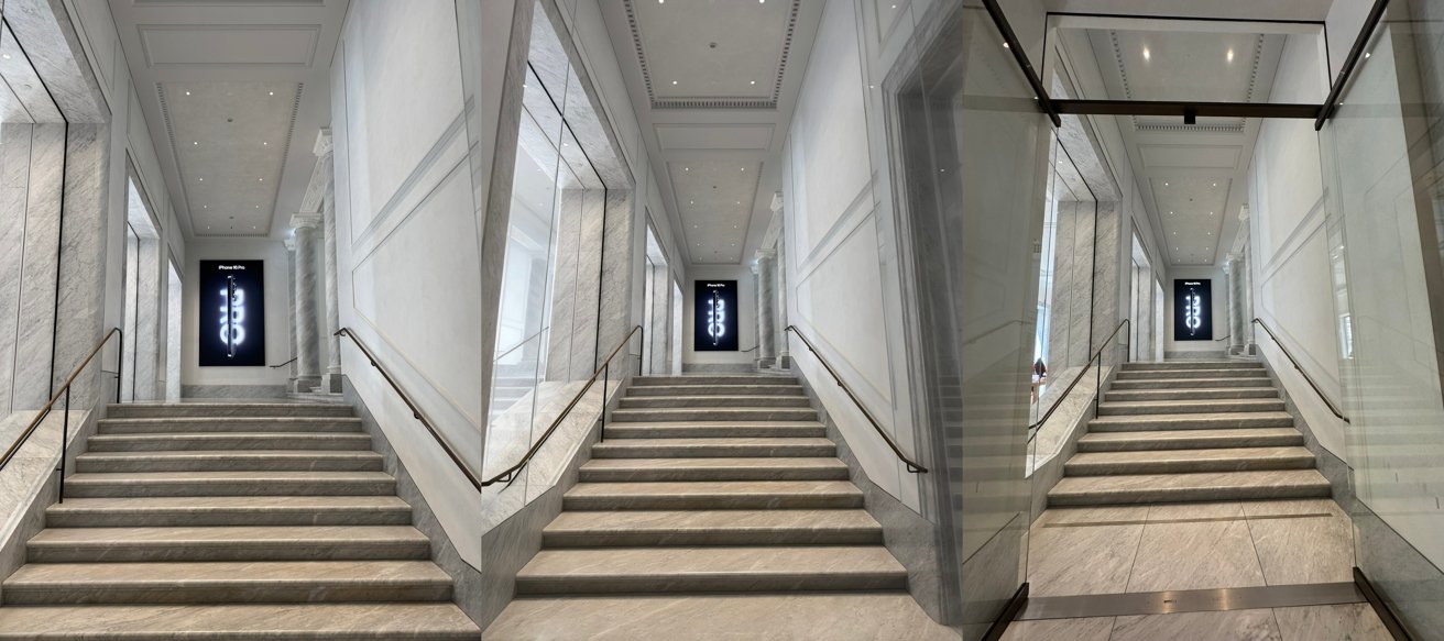 Wide marble staircase in a modern building, flanked by glass and white walls, with metal railings and a dark vertical sign glowing at the top landing