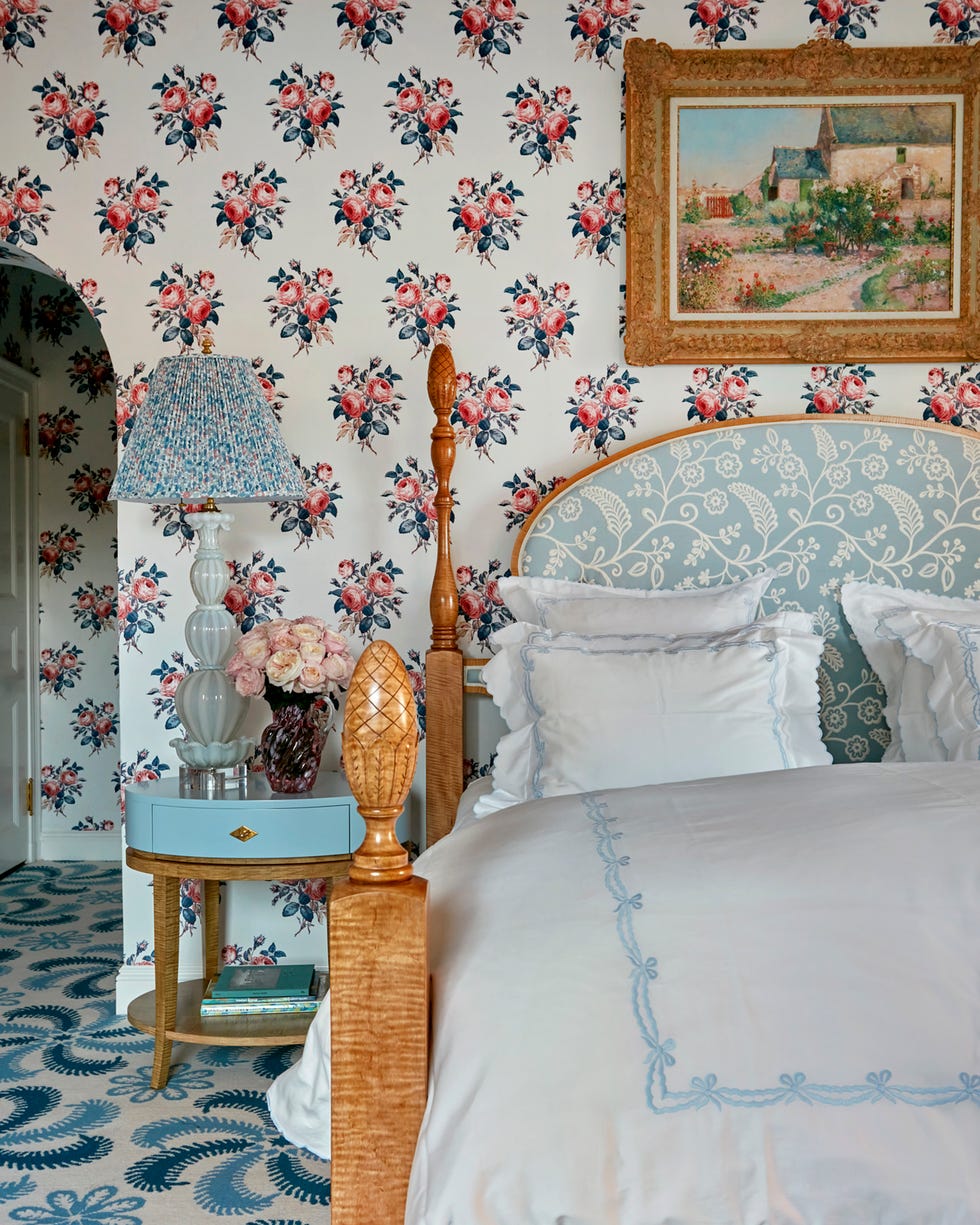 Bedroom with floral wallpaper and wood bed with white and blue linens Bedroom with floral wallpaper and wood bed with white and blue linens