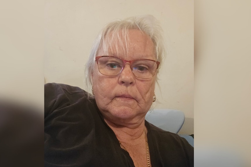 Image of Sue Smith who has a fringe and wears glasses and a tshirt looks at camera with mouth closed.