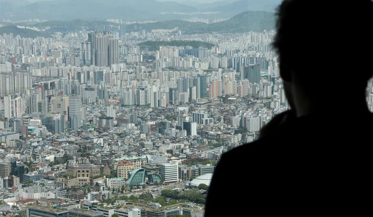 A visitor looks out over apartment complexes from Mount Nam in Seoul, May 8. Yonhap