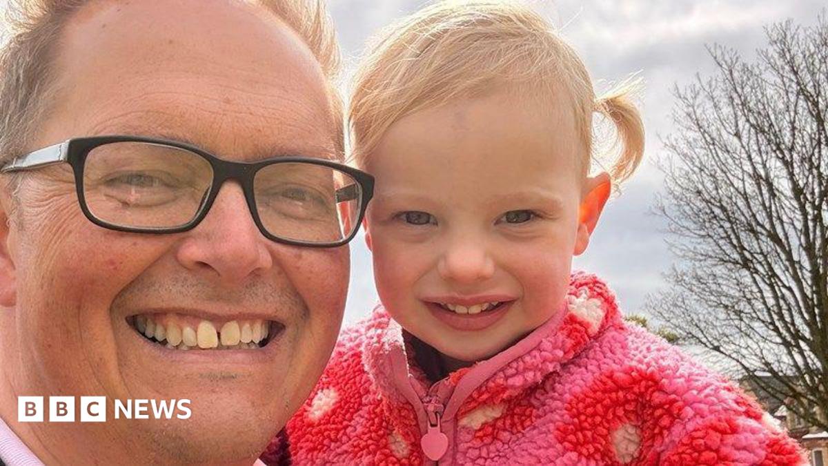Close-up of Dan Williams, who is wearing glasses, holding his granddaughter.