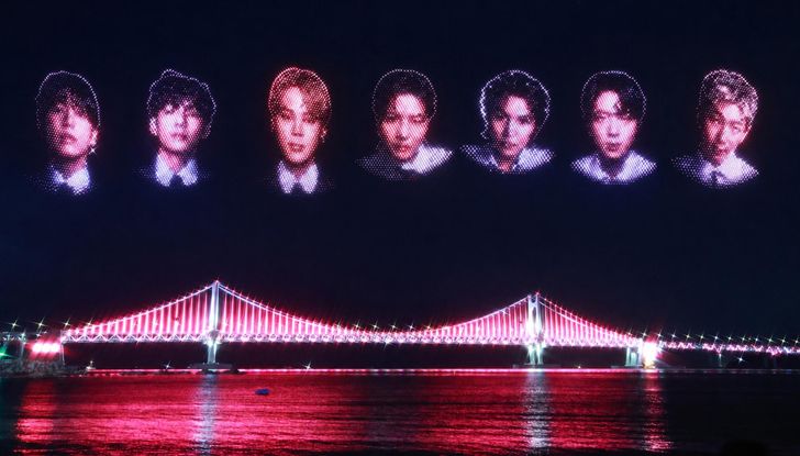 Drone formations depicting the faces of members of BTS light up the night sky above Gwangalli Beach in Busan's Suyeong District on Friday, ahead of the group's two-night concert at Asiad Main Stadium. Yonhap