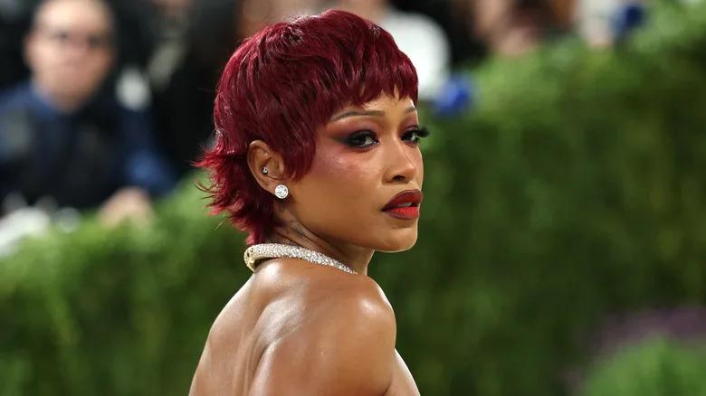 Keke Palmer poses with dark red hair and matching makeup